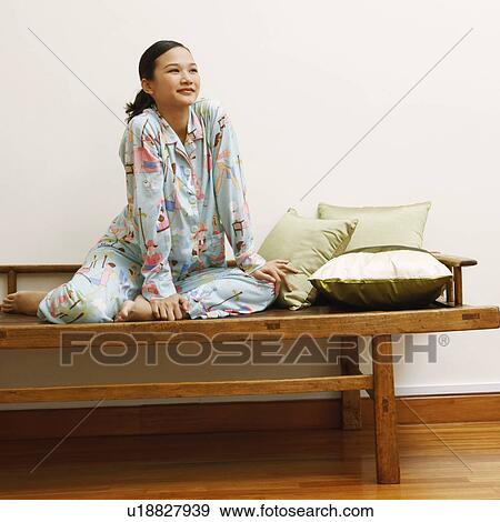 Stock Photo - Young woman sitting on a bench and smiling. Fotosearch