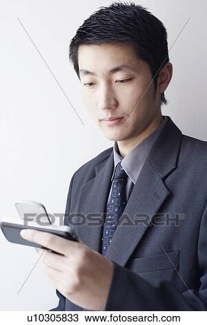 Stock Image - Close-up of a businessman looking at a mobile phone. Fotosearch