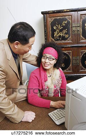 Stock Photograph - Close-up of a businesswoman using a computer with a businessman sitting beside her. Fotosearch