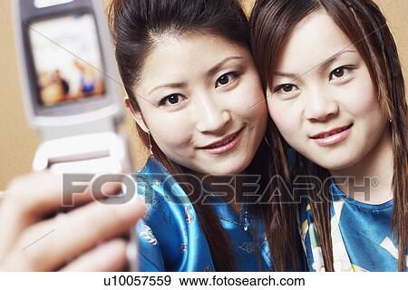 Close-up of a teenage girl and a young woman taking a photograph of themselves View Large Photo Image Stock Photo - Close-up of a teenage girl and a young woman taking a photograph of themselves. Fotosearch