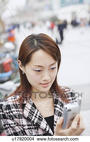 Close-up of a young woman holding a mobile phone View Large Photo Image Picture - Close-up of a young woman holding a mobile phone. Fotosearch