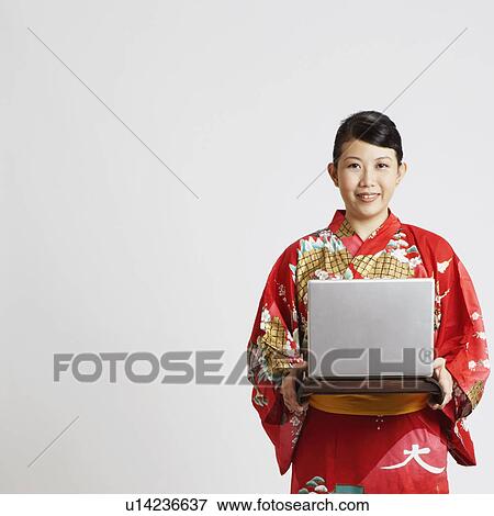 Stock Photo - Close-up of a young woman holding a laptop on a tray. Fotosearch