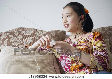 Picture - Close-up of a young woman listening to music. Fotosearch
