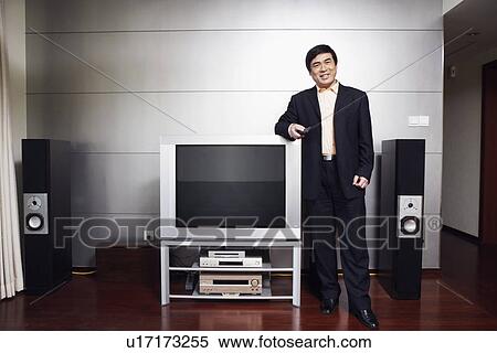 Portrait of a businessman standing by the side of a television smiling View Large Photo Image Stock Photography - Portrait of a businessman standing by the side of a television smiling. Fotosearch