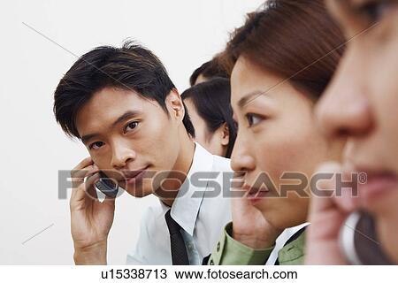 Stock Image - Portrait of a businessman talking on a mobile phone with his colleagues. Fotosearch
