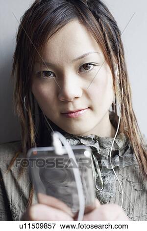 Stock Photo - Portrait of a young woman listening to an MP3 player. Fotosearch