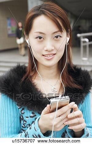 Portrait of a young woman listening to an MP3 player View Large Photo Image Stock Photo - Portrait of a young woman listening to an MP3 player. Fotosearch
