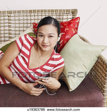 Stock Photograph - Portrait of a young woman listening to an MP3 player. Fotosearch