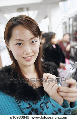 Stock Photography - Portrait of a young woman operating a mobile phone with a digitized pen. Fotosearch