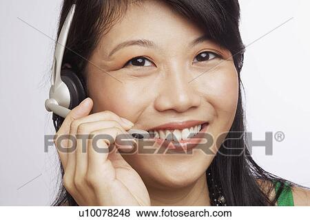 Stock Photo - Portrait of a young woman smiling and wearing a headset. Fotosearch