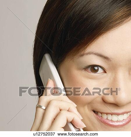 Portrait of a young woman talking on a mobile phone and smiling View Large Photo Image Stock Photo - Portrait of a young woman talking on a mobile phone and smiling. Fotosearch