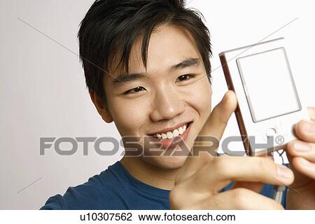 Stock Image - Close-up of a young man taking a picture of himself . Fotosearch