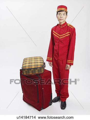 Picture - Portrait of a bellhop standing with luggage. Fotosearch