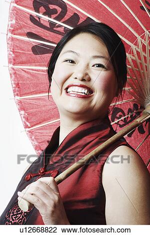 Stock Image - Portrait of a mid adult woman holding a parasol. Fotosearch