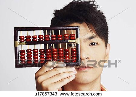 Stock Image - Portrait of a young man holding an abacus. Fotosearch