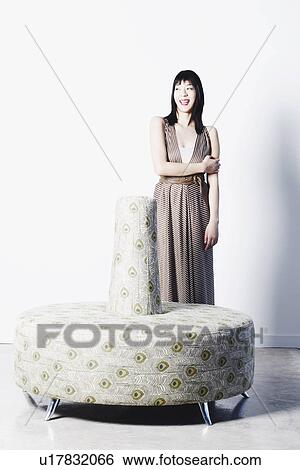 Portrait of a young woman smiling behind a couch View Large Photo Image Stock Photograph - Portrait of a young woman smiling behind a couch. Fotosearch