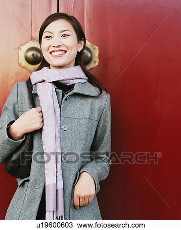 Stock Image - Close-up of a young woman standing and smiling. Fotosearch