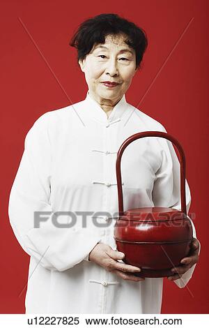 Stock Photography - Portrait of a mature woman holding an antique basket. Fotosearch