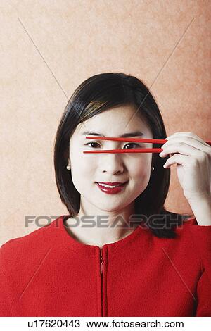 Portrait of a young woman holding chopsticks in front of her face View Large Photo Image Stock Image - Portrait of a young woman holding chopsticks in front of her face. Fotosearch