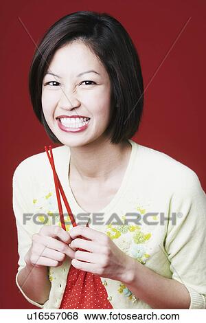 Portrait of a young woman holding chopsticks View Large Photo Image Stock Photo - Portrait of a young woman holding chopsticks. Fotosearch
