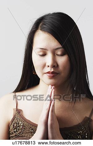 Stock Image - Close-up of a young woman in a prayer position. Fotosearch