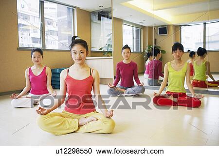 Stock Image - Four young women sitting in the lotus position. Fotosearch