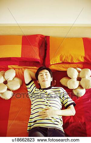 High angle view of a young man sleeping with his hand behind his head View Large Photo Image Stock Image - High angle view of a young man sleeping with his hand behind his head. Fotosearch