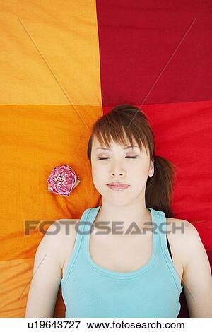 Stock Photo - High angle view of a young woman sleeping on the bed. Fotosearch