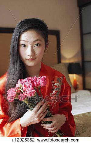 Stock Image - Portrait of a young woman holding a bunch of flowers. Fotosearch