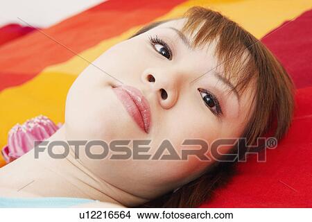 Picture - Portrait of a young woman lying on the bed. Fotosearch