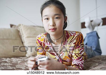 Portrait of a young woman lying on the bed listening to music View Large Photo Image Stock Image - Portrait of a young woman lying on the bed listening to music. Fotosearch