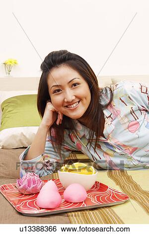 Portrait of a young woman lying on the bed and smiling View Large Photo Image Stock Photograph - Portrait of a young woman lying on the bed and smiling. Fotosearch