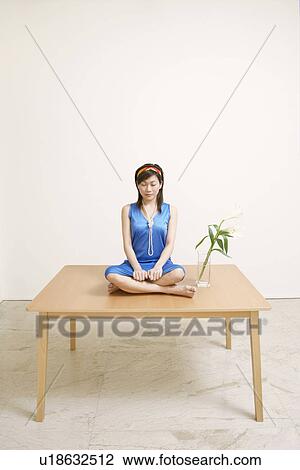 Young woman sitting on the table with her eyes closed View Large Photo Image Stock Image - Young woman sitting on the table with her eyes closed. Fotosearch