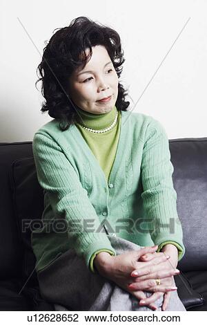 Businesswoman sitting on a couch thinking View Large Photo Image Stock Image - Businesswoman sitting on a couch thinking. Fotosearch