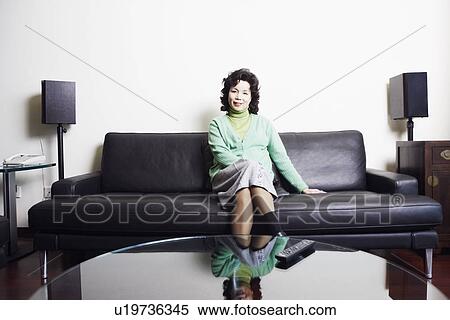 Stock Photography - Portrait of a businesswoman sitting on a couch smiling. Fotosearch