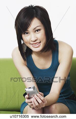 Stock Photography - Portrait of a young woman holding a mobile phone. Fotosearch