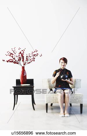 Stock Photograph - Portrait of a young woman holding a tea kettle. Fotosearch