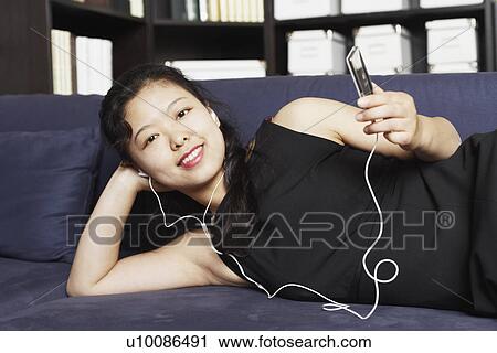 Portrait of a young woman listening to music on headphones View Large Photo Image Stock Image - Portrait of a young woman listening to music on headphones. Fotosearch