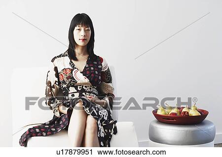 Portrait of a young woman sitting on a couch View Large Photo Image Stock Image - Portrait of a young woman sitting on a couch. Fotosearch