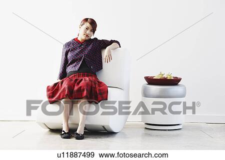 Stock Photo - Portrait of a young woman sitting on a couch. Fotosearch