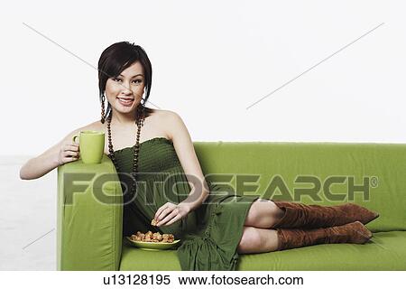 Stock Photography - Portrait of a young woman sitting on a couch smiling. Fotosearch