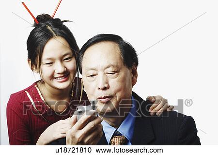 Stock Image - Close-up of a granddaughter standing behind her grandfather. Fotosearch
