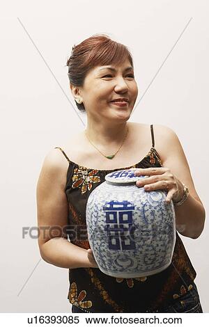 Close-up of a mature woman holding an urn View Large Photo Image Stock Photography - Close-up of a mature woman holding an urn. Fotosearch