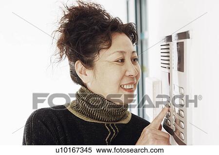 Stock Photography - Close-up of a mature woman using an intercom. Fotosearch