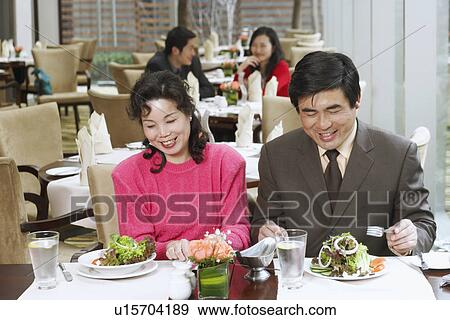 Stock Photo - Mature couple sitting in a restaurant smiling. Fotosearch