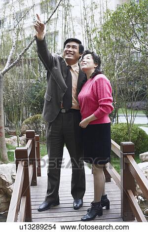Mature man pointing to a mature woman smiling View Large Photo Image Picture - Mature man pointing to a mature woman smiling. Fotosearch