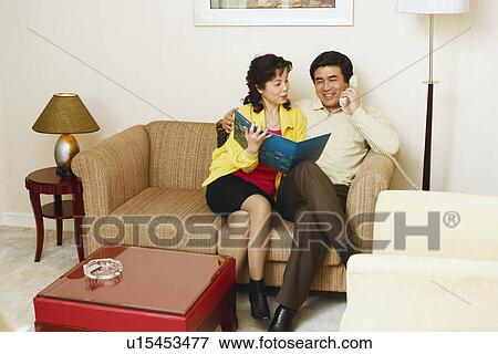 Stock Photo - Mature man sitting on a couch with a mature woman talking on the telephone. Fotosearch