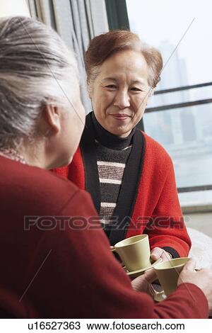 Mature woman facing a senior woman holding a cup of tea View Large Photo Image Stock Image - Mature woman facing a senior woman holding a cup of tea. Fotosearch