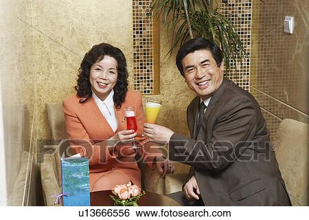 Stock Photograph - Portrait of a businessman and businesswoman sitting in a restaurant raising a toast. Fotosearch