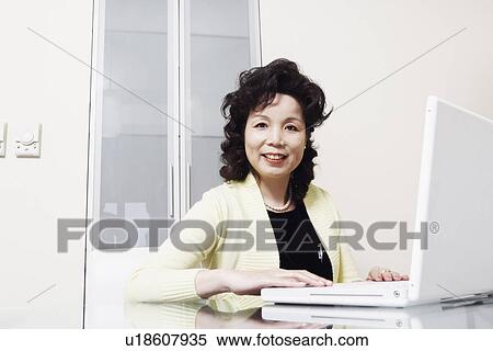 Stock Photography - Portrait of a businesswoman using a laptop smiling. Fotosearch
